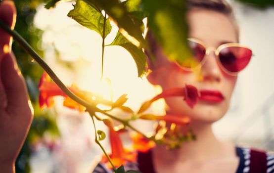 beautiful woman in glasses near red flowers on the street and red sundress striped t-shirt. High quality photo