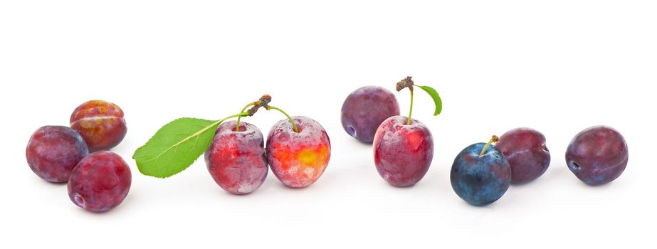 Ripe plums with leaves close up on white background.
