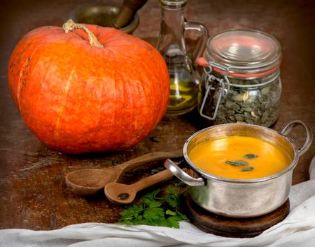 Bowl of pumpkin soup on rustic wooden background.