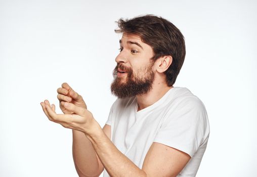 Emotional man with a beard holds his hands near his face on a light background cropped view. High quality photo