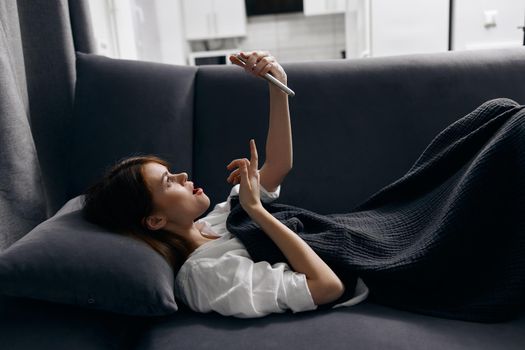 woman with mobile phone resting lying on the sofa indoors. High quality photo