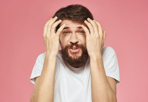 Portrait of a guy in a white t-shirt on a pink background cropped view of fun emotions. High quality photo