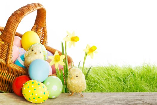 Easter basket with eggs on green meadow with flowers