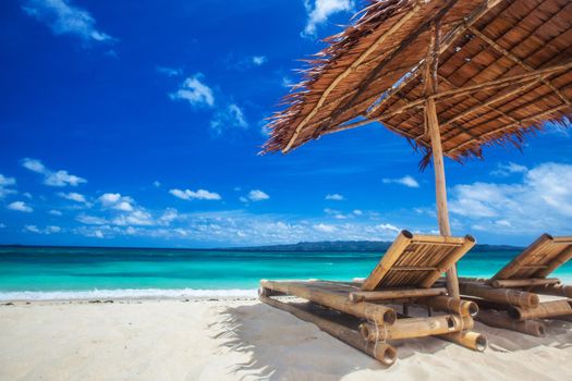 Beach chairs and umbrella on a beautiful tropical sea beach, view with copy space