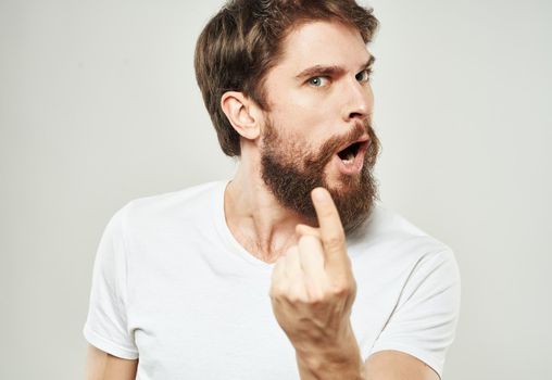 Aggressive man in a white T-shirt irritability emotions light background. High quality photo