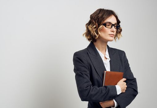 Business woman in a classic suit with a book in her hands on a light background indoors. High quality photo