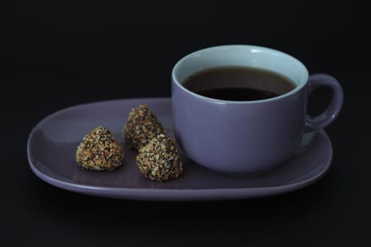 Tea cup with a saucer in the style of Provence on a black background. Purple on black.