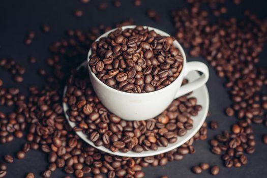 coffee beans In a saucer and in a cup of coffee on a gray background female hand macro photography. High quality photo