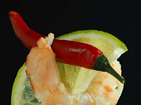 The prawn is royal. Macrophotography texture of shrimp meat with a slice of lime and chilli on a black background. High quality photo