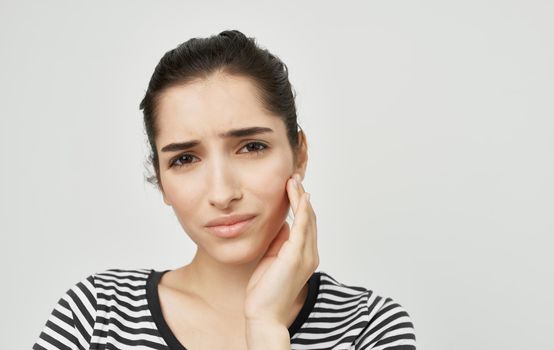 woman in striped t-shirt holding face dental problems pain discontent. High quality photo
