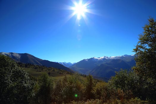 Beautiful natural landscape. The sun against the blue sky and mountains.