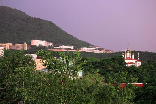 Rainbow over the city at sunset. Mountain landscape with a rainbow. Vertical image.