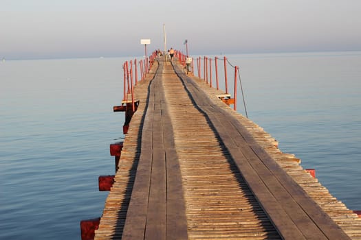 A seascape with a wooden bridge with a prospect in the sea.