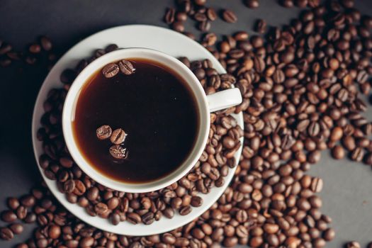 a cup with a fragrant drink and coffee beans around a saucer top view. High quality photo