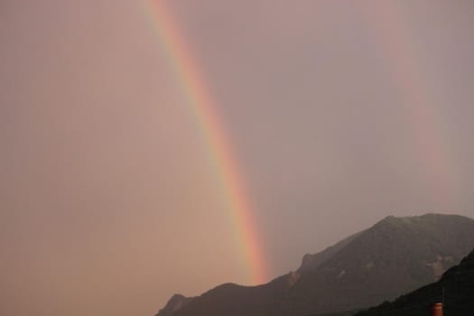 Rainbow over the city at sunset. Mountain landscape with a rainbow. Vertical image.