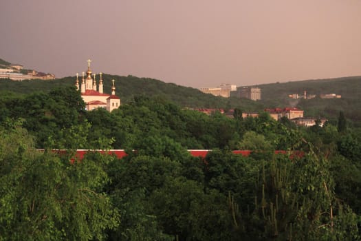 Rainbow over the city at sunset. Mountain landscape with a rainbow. Vertical image.