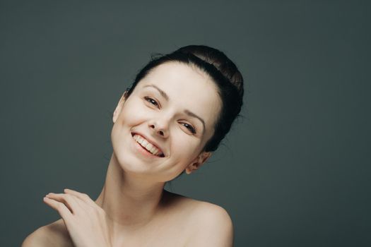 brunette with bare shoulders gathered hair hand near face. High quality photo