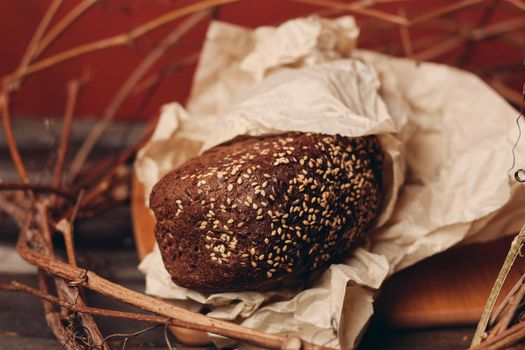 Loaf of Bread In a paper package lies on branches in a nest on a wooden table. High quality photo