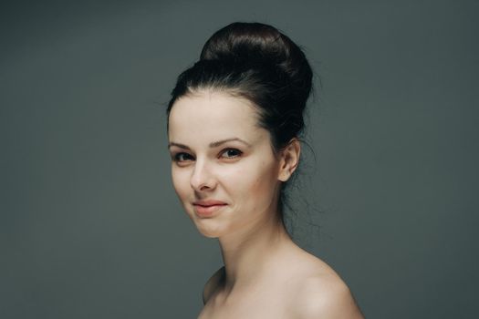 beautiful woman smiling on gray background naked shoulders cropped view hairstyle. High quality photo