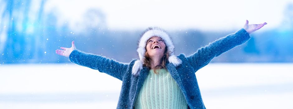 Young attractive woman happy with the falling snow in winter nature