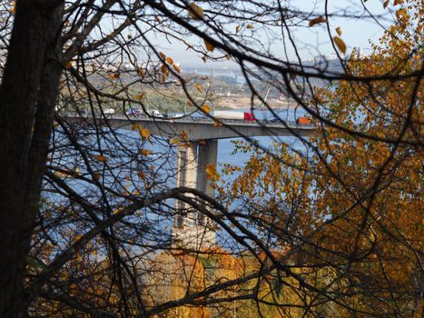 A large transport bridge over the river. City by the river.