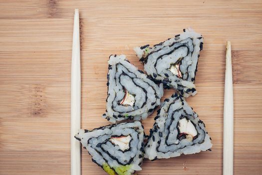 triangular sushi rolls chopsticks wooden background. High quality photo