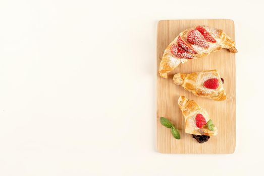 delicious golden croissants filled with strawberry jam. Flat lay, top view, copy space.