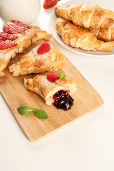 delicious golden croissants filled with strawberry jam on wooden board. Flat lay, top view