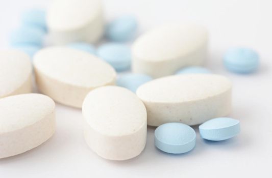 A close up of group of pills on white background.