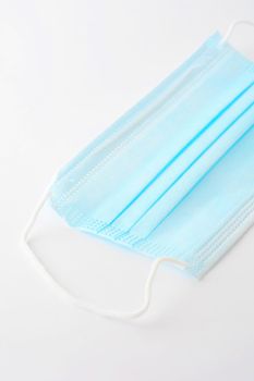 Blue surgical face mask (currently protecting against Coronavirus Covid-19) on white background.