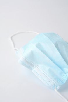 Blue surgical face mask (currently protecting against Coronavirus Covid-19) on white background.