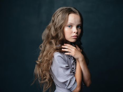 Portrait of a beautiful girl in a gray sundress on a dark background and a curly long hair model. High quality photo
