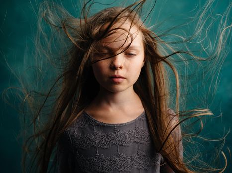 Pretty little girl with disheveled hair on a turquoise background. High quality photo