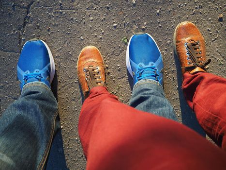 Two pairs of legs in sneakers on the pavement. A pitch from above. A man and a woman.