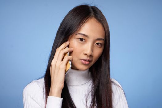 woman korean appearance talking on mobile phone on blue background. High quality photo