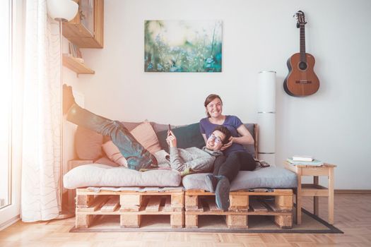 Young woman and man sitting on cozy palette sofa, living room