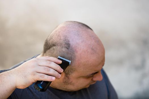 Male shaving or trimming his hair using a hair clipper or electric razor