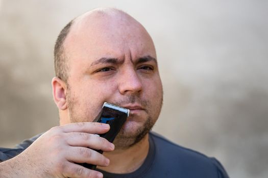 Male shaving or trimming his beard using a hair clipper or electric razor