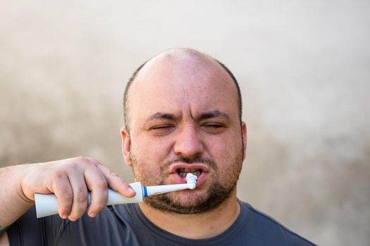 Male brushing his teeth with electric toothbrush