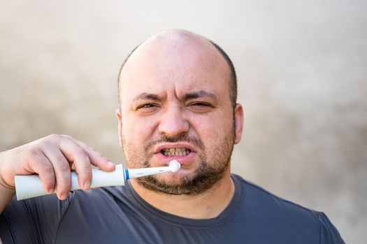 Male brushing his teeth with electric toothbrush