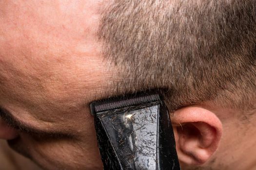 Man shaving or trimming his hair using a hair clipper