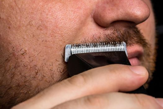 Man shaving or trimming his beard using a hair clipper