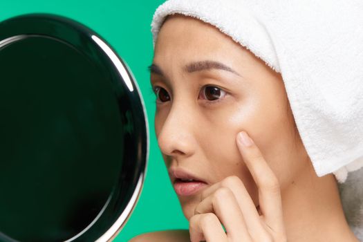 woman of asian appearance towel on head clean skin touching face mirror with hands. High quality photo