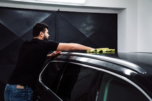 man cleans the car body with a towel. auto care.