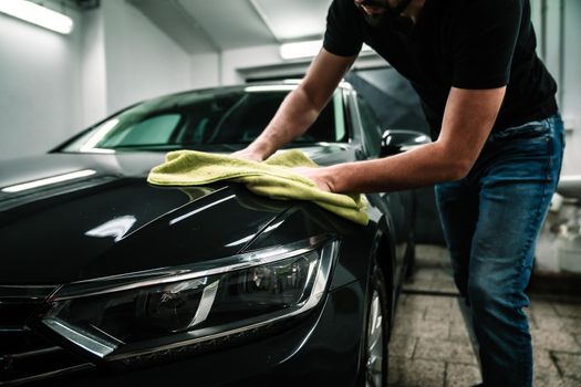 man cleans the car body with a towel. auto care.