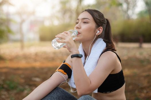 Young woman athlete takes a break, drinking water, out on a run on a hot day