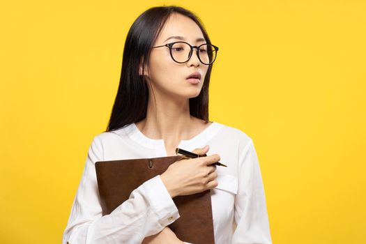 asian woman with notebook in hand learning student yellow background. High quality photo