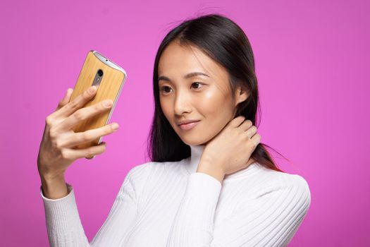 asian woman holding phone he communication technology internet pink background. High quality photo