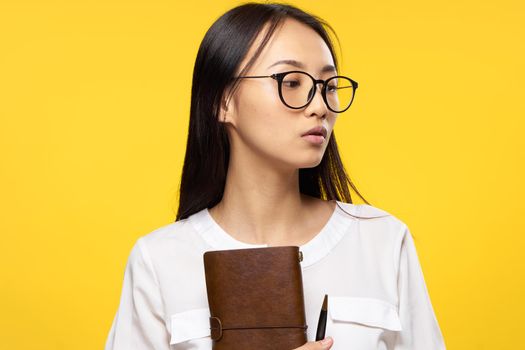 Business woman in glasses holding notepad in hands official yellow isolated background. High quality photo