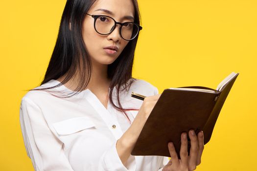 woman of asian appearance wearing glasses elegant style notepad in student hands. High quality photo